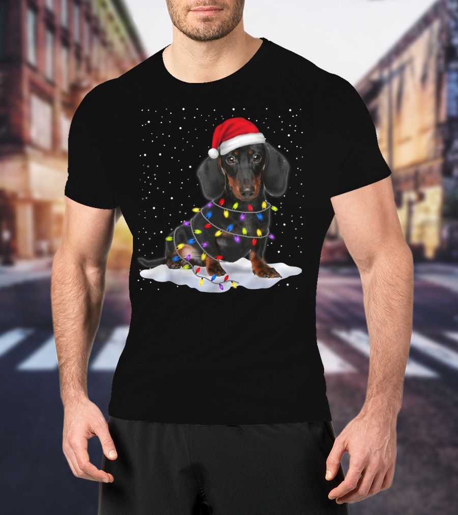 Dachshund Santa Hat Wrapped In Christmas Tree Lights In Snow With Falling Snowflakes T-Shirt
