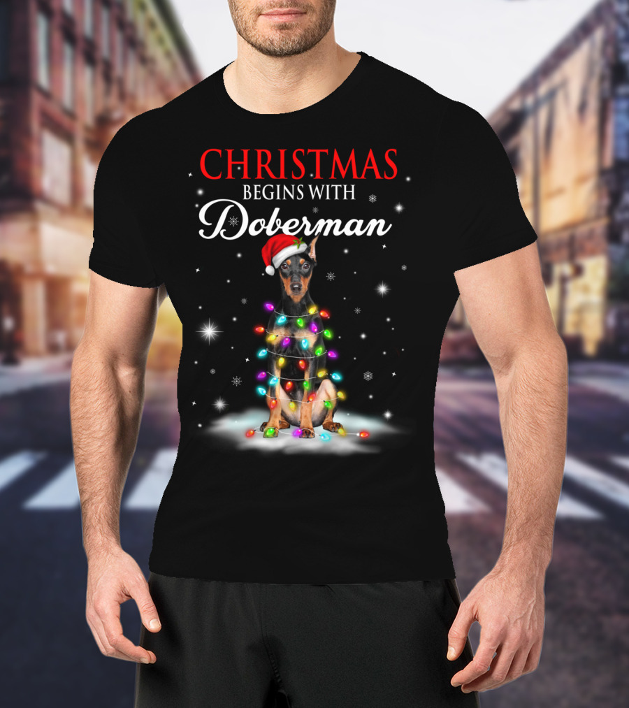 Christmas Begins With Doberman Wrapped In Holiday Lights And Santa Hat Snowflakes T-Shirt